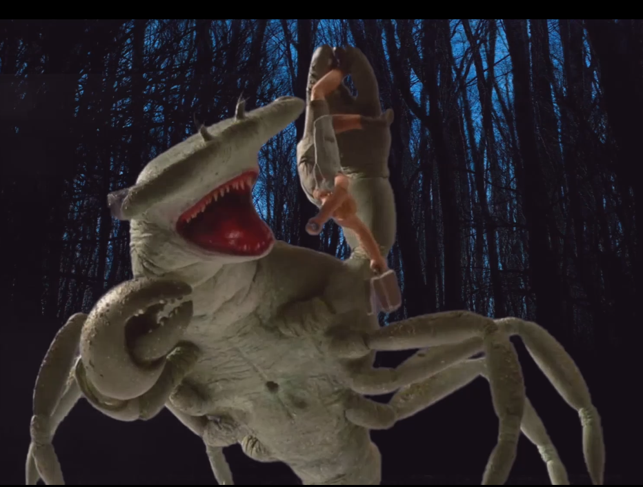 Stop-Motion animiertes Mischwesen aus Hammerhai und Hummer hält eine menschlich wirkende Figur mit einem Koffer in einer der Scheren.