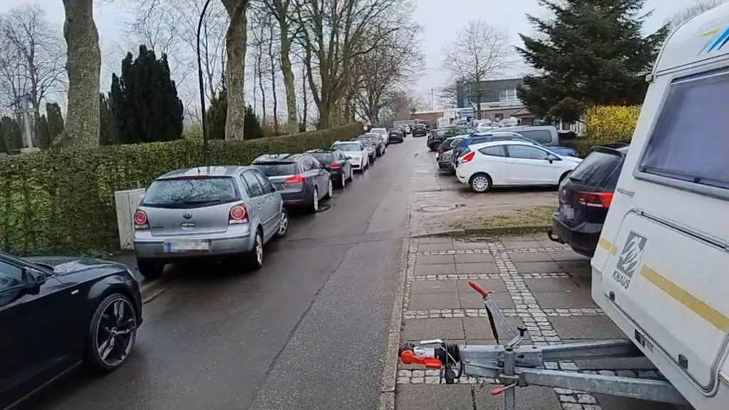 Die selbe Straße aus der Perspektive neben dem Wohnwagen. So wird die Behinderung durch die falsch geparkten Autos noch deutlicher.
